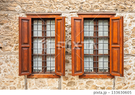 Rustic stone wall with wooden shuttered windows 133630605