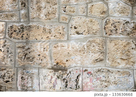 Close-up of textured beige stone wall with weathered surface patterns Close-up of textured beige stone wall with weathered surface patterns 133630668