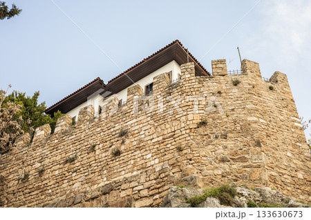 Historic stone fortress wall with rooftop structure under clear sky Historic stone fortress wall with rooftop structure under clear sky 133630673