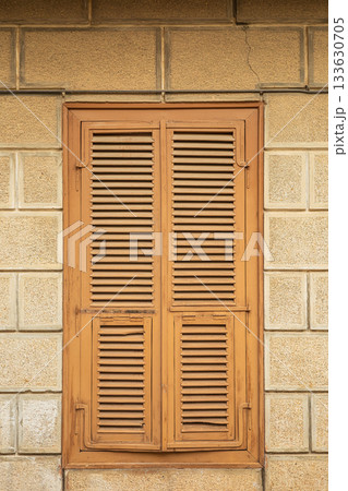 Rustic wooden shuttered window on stone building wall 133630705