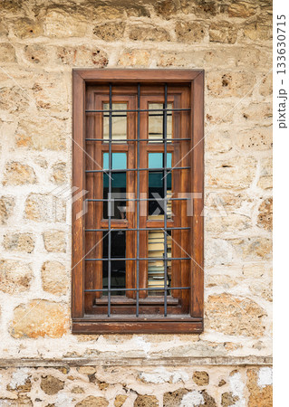 Rustic wooden window with bars on stone wall 133630715