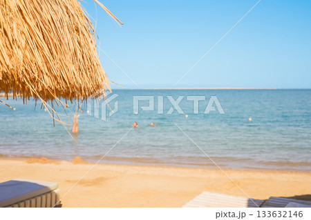 Three people swimming near sandy beach umbrella on blurred background 133632146
