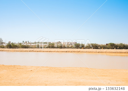 Desert landscape with water and distant buildings 133632148