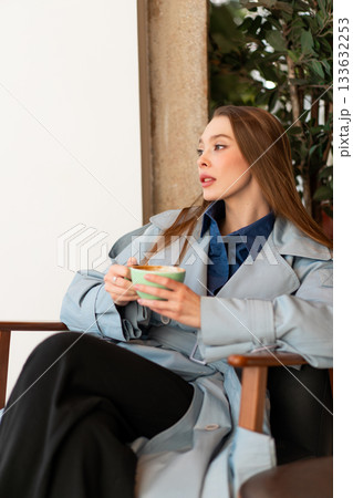 Young businesswoman in stylish coat holding coffee Young businesswoman in stylish coat holding coffee 133632253
