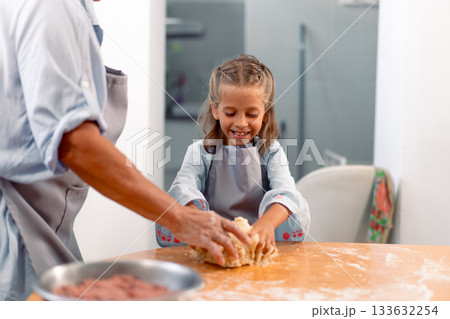 Smiling girl kneading dough with grandmother on Smiling girl kneading dough with grandmother on 133632254