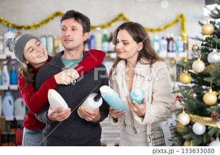 Father, mother and daughter choose shampoo or shower gel in supermarket Father, mother and daughter choose shampoo or shower gel in supermarket 133633080