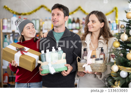 Cheerful family choosing self-care gift sets in Christmas decorated store Cheerful family choosing self-care gift sets in Christmas decorated store 133633093