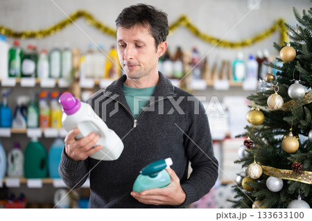 Man chooses spray glass cleaner and detergent in supermarket before Christmas 133633100