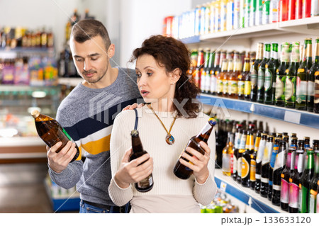 In Russian goods store, woman with husband choose bottle of beer In Russian goods store, woman with husband choose bottle of beer 133633120