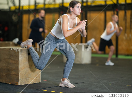 Sportive young girl practicing one leg squats with box during crossfit workout 133633159