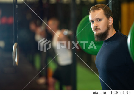 Determined young guy working out with weight rod during crossfit workout Determined young guy working out with weight rod during crossfit workout 133633199