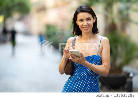Young woman with mobile phone on city street Young woman with mobile phone on city street 133633288