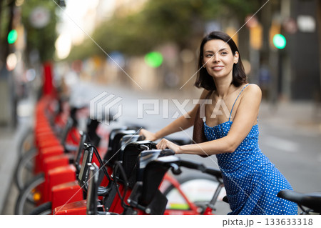 Young woman on rented bike on city street 133633318