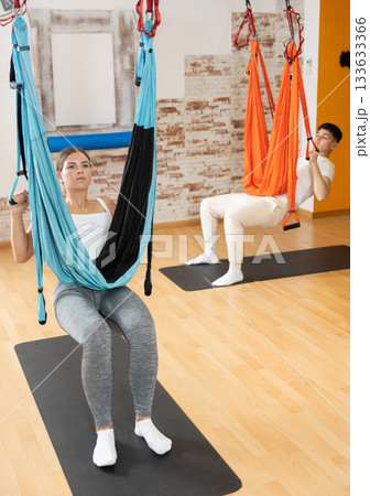 Man visitor performs exercises in hanging position on Pilates slings hammock Man visitor performs exercises in hanging position on Pilates slings hammock 133633366