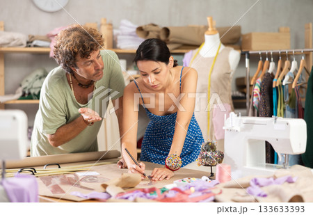 Woman and man tailor draw dress pattern with curve ruler on paper 133633393