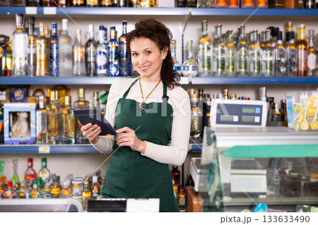 Woman works as salesperson in alcohol department of Russian store. 133633490