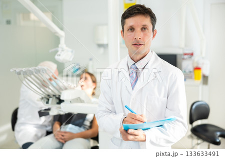 Adult male nurse taking notes in dental office 133633491