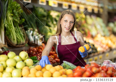 Young woman seller puts peaches in vegetable shop 133633519