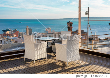 Coastal rooftop dining with ocean view and white furniture on wooden deck Coastal rooftop dining with ocean view and white furniture on wooden deck 133633525