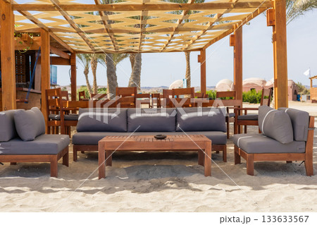 Outdoor lounge area with wooden furniture on a sunny beach setting 133633567