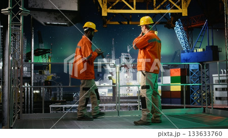 Offshore engineer coordinating via walkie talkie during oil production operations, natural gas emission monitoring under northern lights. Compliance with oil extraction rules. Offshore engineer coordinating via walkie talkie during oil production operations, natural gas emission monitoring under northern lights. Compliance with oil extraction rules. 133633760