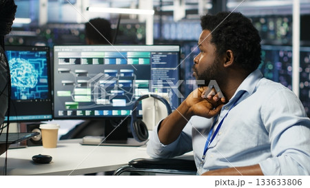 Data center engineer in wheelchair and colleague oversee automated tasks using node tree programming tool. Inclusive server farm team adjusts system settings based on AI analytics, camera B Data center engineer in wheelchair and colleague oversee automated tasks using node tree programming tool. Inclusive server farm team adjusts system settings based on AI analytics, camera B 133633806