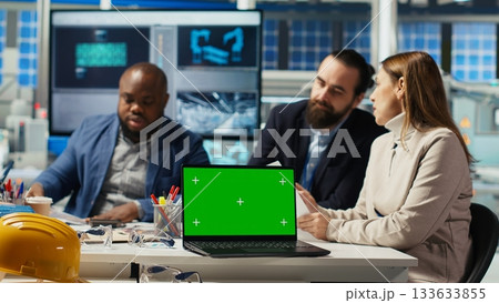 Factory engineers use green screen laptop to check PV materials parameters, improving solar panel durability. Researcher develop efficient sustainable energy solutions using mockup notebook, camera B 133633855