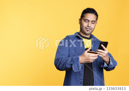 Indian male model excited about online shopping on website with his credit card, checking his balance and processing the payment for things on sale. Young adult entering banking credentials. Indian male model excited about online shopping on website with his credit card, checking his balance and processing the payment for things on sale. Young adult entering banking credentials. 133633913