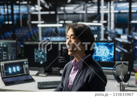 System administrator in data center using PC, managing AI training datasets. Asian man using computer program to oversee machine learning in server room supporting scalable infrastructure for AI apps System administrator in data center using PC, managing AI training datasets. Asian man using computer program to oversee machine learning in server room supporting scalable infrastructure for AI apps 133633967