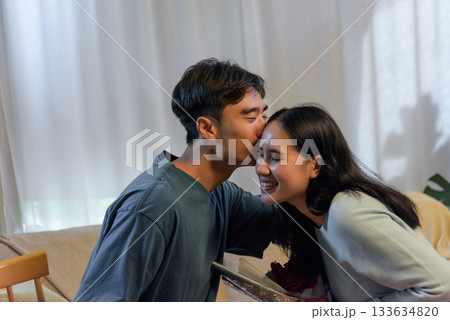 Young couple happy in love man kisses woman at home romantic valentine day moment showing deep affection celebrating connection sweet gesture creates joyful memory for perfect for anniversaries. Young couple happy in love man kisses woman at home romantic valentine day moment showing deep affection celebrating connection sweet gesture creates joyful memory for perfect for anniversaries. 133634820