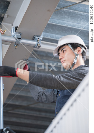 天井が近い高所の足場で単管パイプを固定するクランプなどの施工作業 鳶職や作業員のイメージ 天井が近い高所の足場で単管パイプを固定するクランプなどの施工作業 鳶職や作業員のイメージ 133635140
