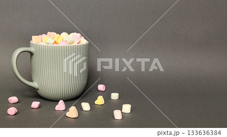 A gray cup with a marshmallow heart on a gray background. Space for text. A gray cup with a marshmallow heart on a gray background. Space for text. 133636384