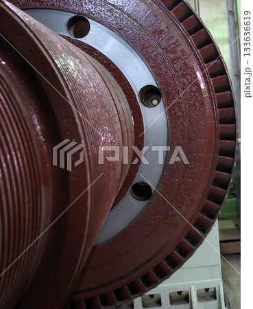A detailed close-up of a large, red industrial turbine component, featuring grooved textures and circular openings. The image showcases the intricate design and powerful scale of heavy machinery 133636619