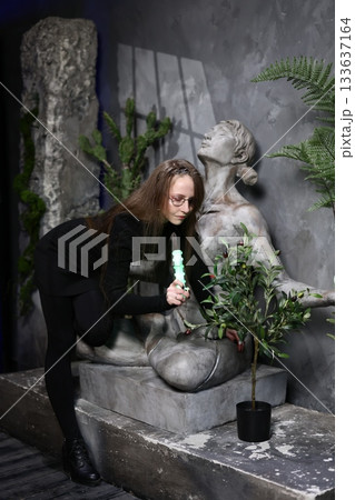 Woman carefully arranging greenery around statue during sunset ambiance Woman carefully arranging greenery around statue during sunset ambiance 133637164