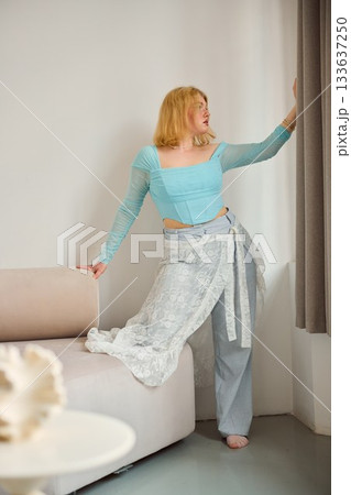 fairhaired woman adjusting, lighthaired woman tidying window treatment in tranquil setting at home fairhaired woman adjusting, lighthaired woman tidying window treatment in tranquil setting at home 133637250
