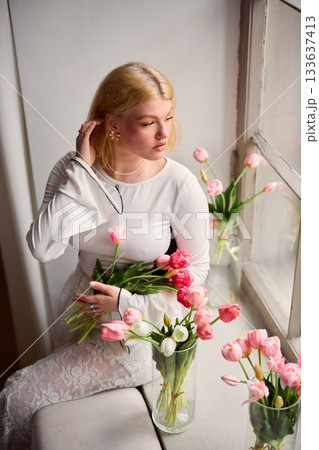 Quiet woman contemplates springtime blooms thoughtfully 133637413