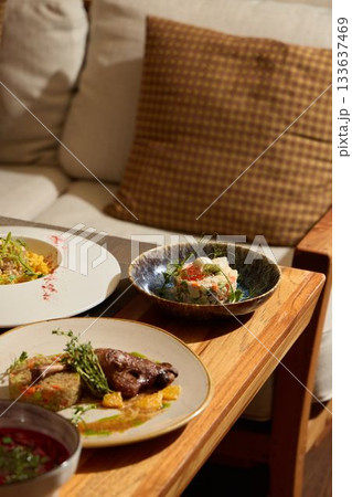 Indulge in an Elegant Dining Experience Featuring Gourmet Dishes Served on a Wooden Table Indulge in an Elegant Dining Experience Featuring Gourmet Dishes Served on a Wooden Table 133637469