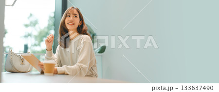 Adult asian business woman using digital tablet working and relax at cafe sitting near window 133637490