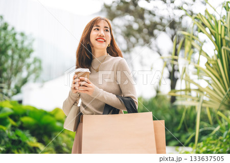 Single beautiful smiling adult business asian woman holding coffee cup and shopping bag 133637505