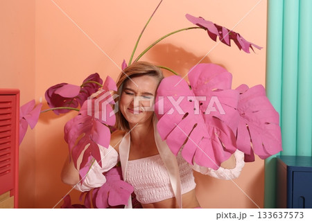Happy woman with pink leaves and playful bright studio atmosphere 133637573