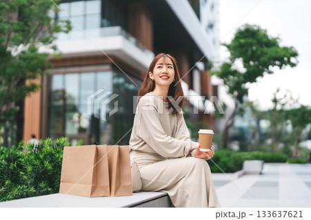 Single adult business asian woman holding coffee cup relax sitting with shopping bag city lifestyle Single adult business asian woman holding coffee cup relax sitting with shopping bag city lifestyle 133637621