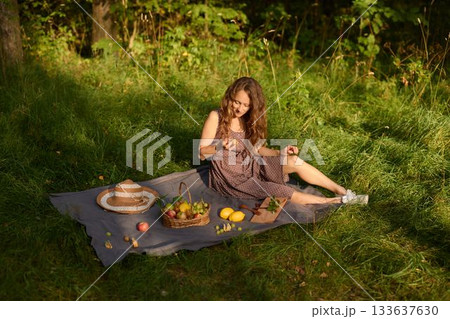Relaxed female savoring peaceful tea amidst fresh fruit and sun Relaxed female savoring peaceful tea amidst fresh fruit and sun 133637630