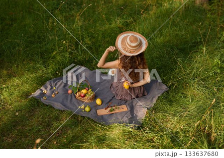 Girl checks fruit, Woman reclining on blanket inspecting orchard produce Girl checks fruit, Woman reclining on blanket inspecting orchard produce 133637680