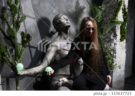 Expressionful woman in black attire observing intricate art installation 133637725