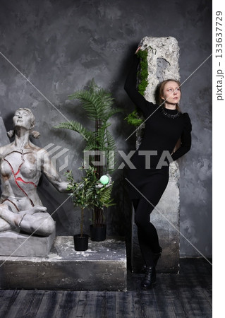 Chic female model poses near classical sculptures and lush ferns Chic female model poses near classical sculptures and lush ferns 133637729
