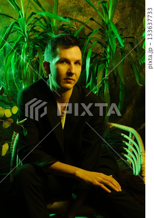 Casual yet sophisticated young man surrounded by vibrant green lights 133637733