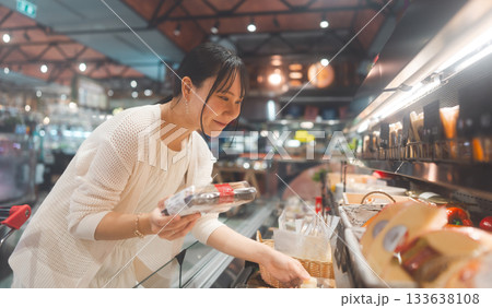 Young adult asian woman consumer choosing cheese dairy products at supermarket store buying food Young adult asian woman consumer choosing cheese dairy products at supermarket store buying food 133638108
