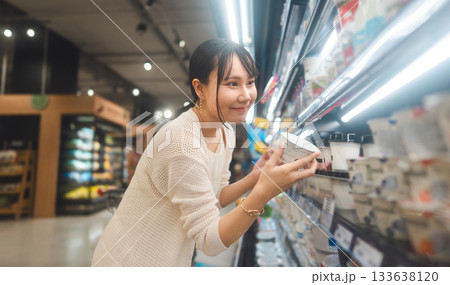 Young asian woman supermarket shopping cart choosing beverage shelf grocery food at department store Young asian woman supermarket shopping cart choosing beverage shelf grocery food at department store 133638120