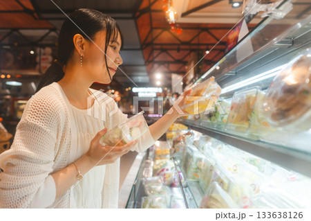 Young asian woman supermarket shopping cart choosing fruits grocery food at department store 133638126