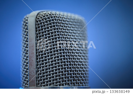 A detailed view of a microphone with a blue backdrop. 133638149
